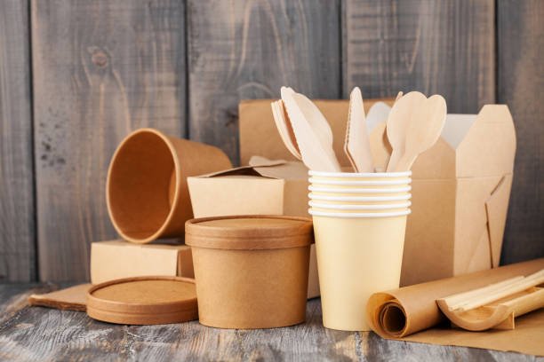 Eco craft paper tableware. Paper cups, dishes, bag, fast food containers and  wooden cutlery on wooden background. Recycling concept. Copy space