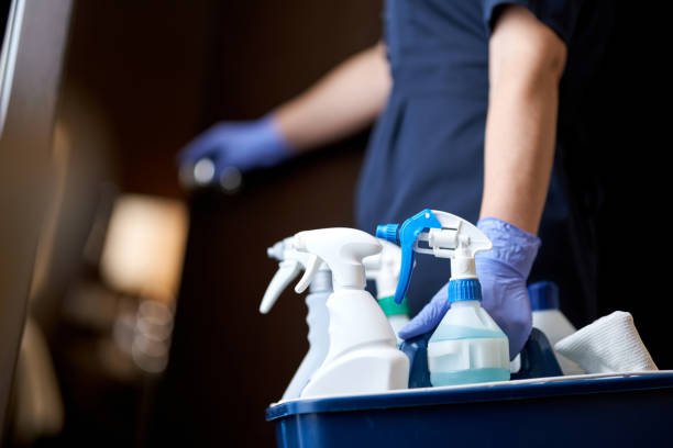 Cropped photo of chambermaid keeping all necessary cleaning and disinfection accessories in hotel room. Hotel service concept