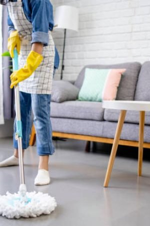 Young woman holding a floor wiper and wiping floor, keeping the daily home hygiene and doing housework.